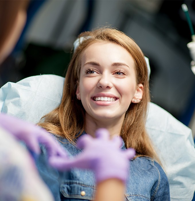 Woman in dental chair smiling at her dentist