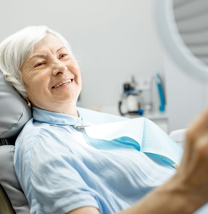 Woman looking at her smile after one visit dental restoration