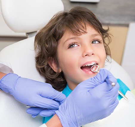 Young person smiling at dentist during children's dentistry exam