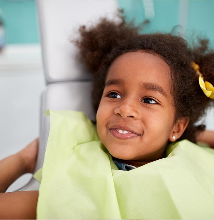 Child in dental chair smiling during first visit