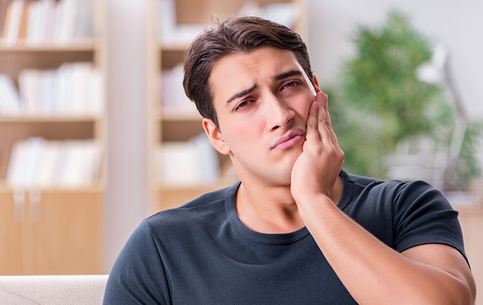 Man with toothache holding cheek