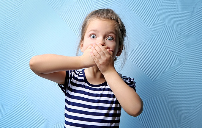 Little girl with knocked out tooth covering her mouth