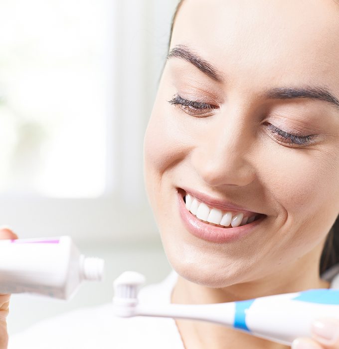 Woman brushing teeth to prevent dental emergencies