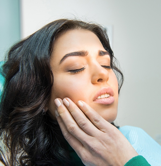 Woman holding jaw during emergency dentistry treatment