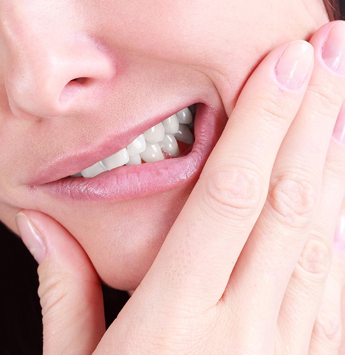 Patient in need of tooth extraction grimacing and holding jaw