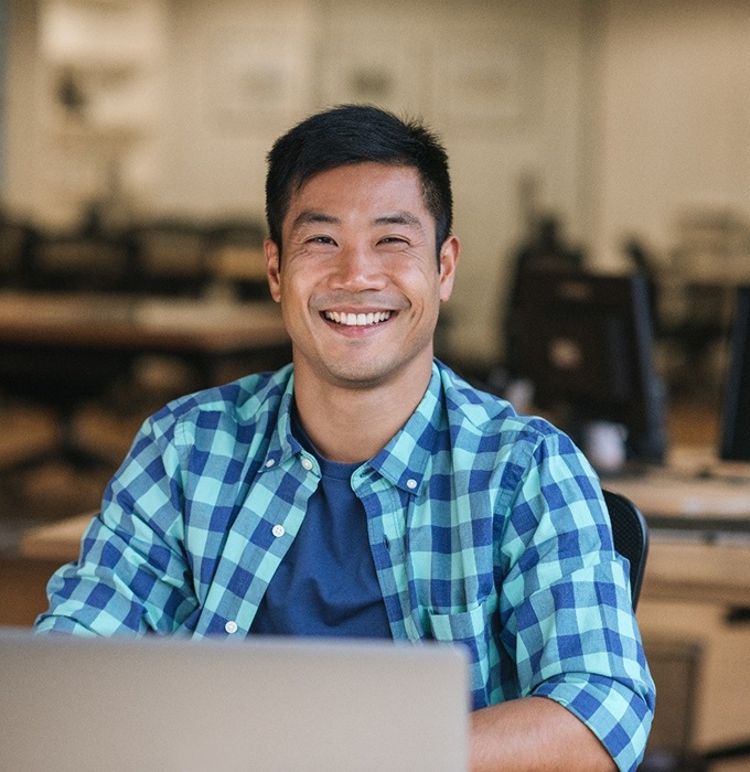 person smiling and sitting at a desk