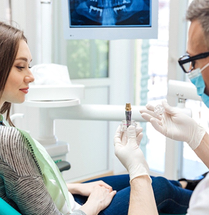 dentist showing a dental implant to a patient