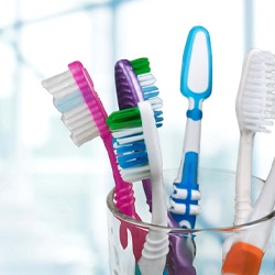 Toothbrushes in a clear glass on bathroom cabinet