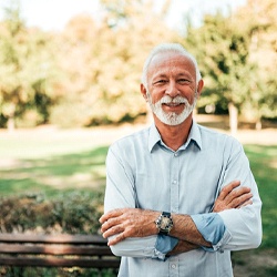 Man with dental implants outside with his arms folded