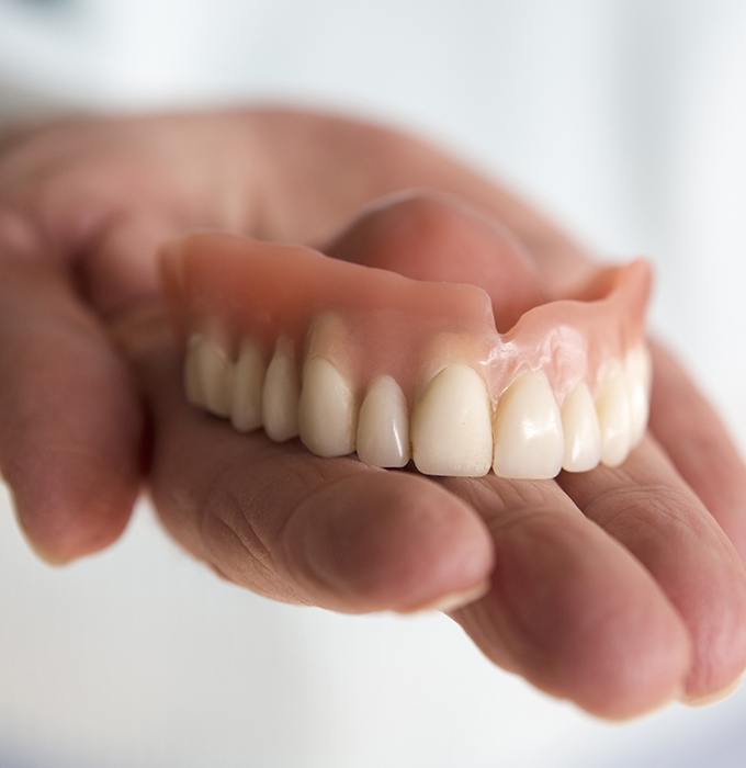 Hand holding a full denture