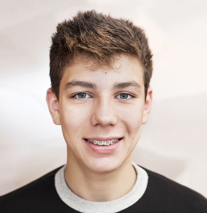 Teen boy with traditional orthodontics smiling