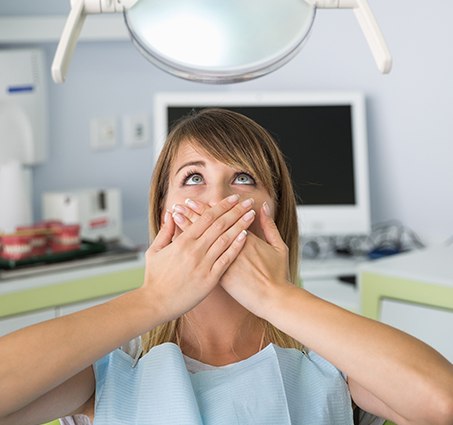 Fearful patient in need of sedation dentistry covering her mouth