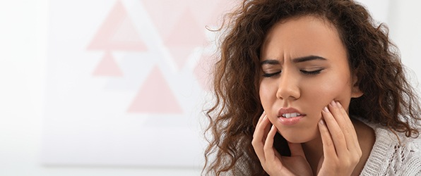 Woman in need of emergency dentistry holding jaw in pain