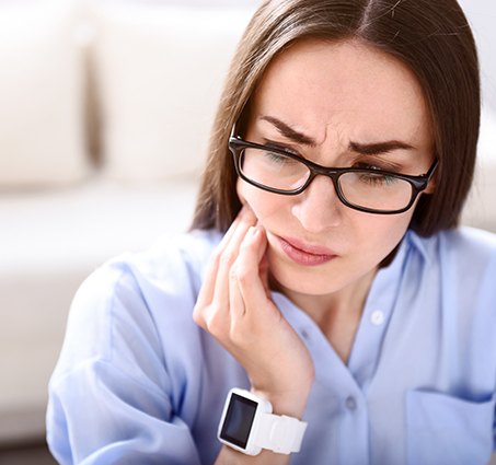 Woman in need of T M J therapy holding her jaw