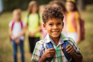 Child with a backpack smiling.