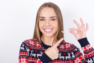 a patient smiling and holding their Invisalign aligner in Chelsea